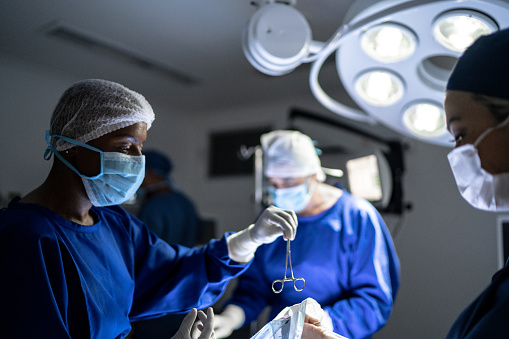 Surgeon passing a scissor to assistant